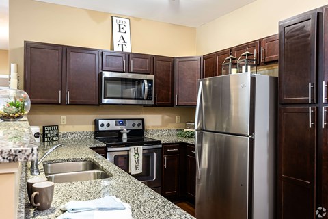 A kitchen with a refrigerator, sink, and cabinets.