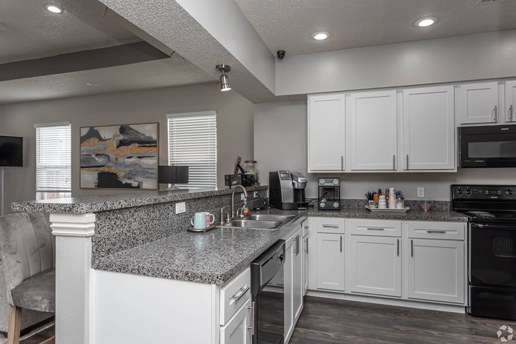 A kitchen with white cabinets and a granite countertop.