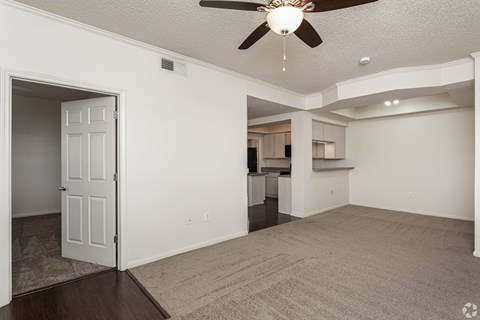 A spacious living room with a ceiling fan and carpeted floor.