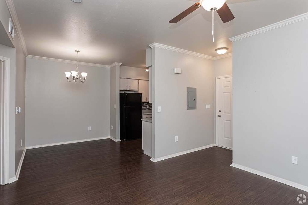 A room with a ceiling fan and a black refrigerator.