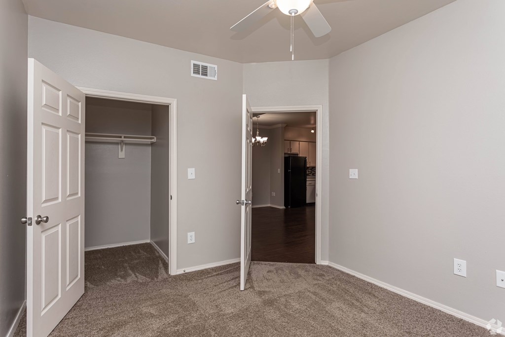 A room with a ceiling fan and a doorway leading to another room.