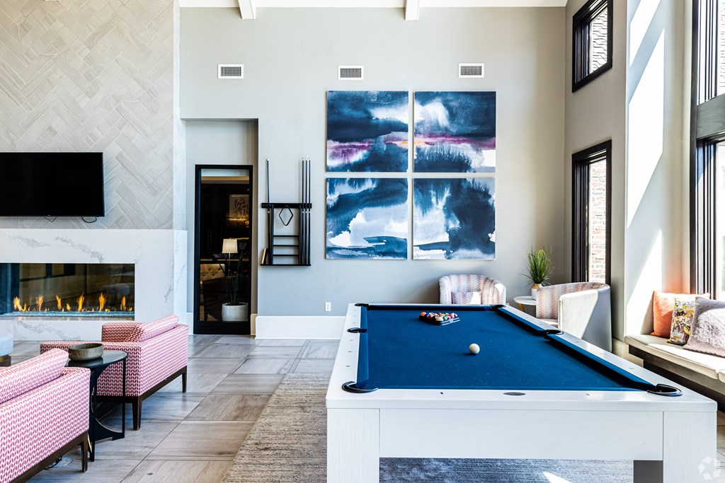 an open living room with a pool table and a fireplace  at Waterside Residences on Quivira, Lenexa, 66215
