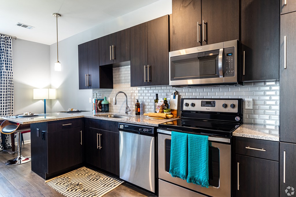 a modern kitchen with stainless steel appliances and dark wood cabinets  at Waterside Residences on Quivira, Lenexa