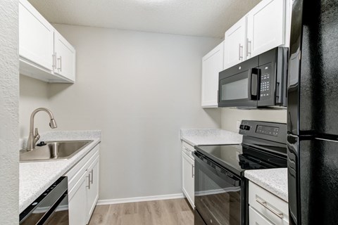 A kitchen with black appliances and white cabinets.