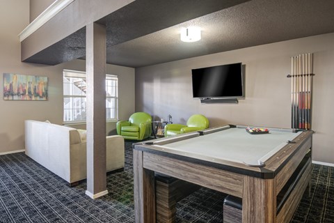 A billiard table is in the middle of a room with a TV and a chair.