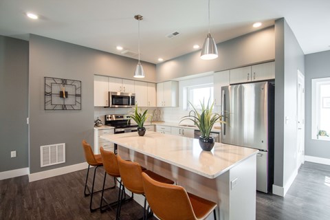 A modern kitchen with a large island and wooden chairs.
