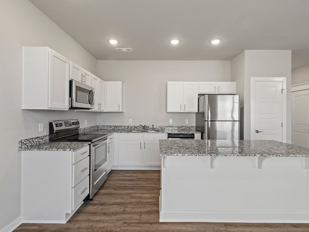 an empty kitchen with white cabinets and granite counter tops at Hillcrest Village, Springdale, AR