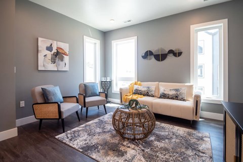 A living room with a white couch, two chairs, and a woven coffee table.