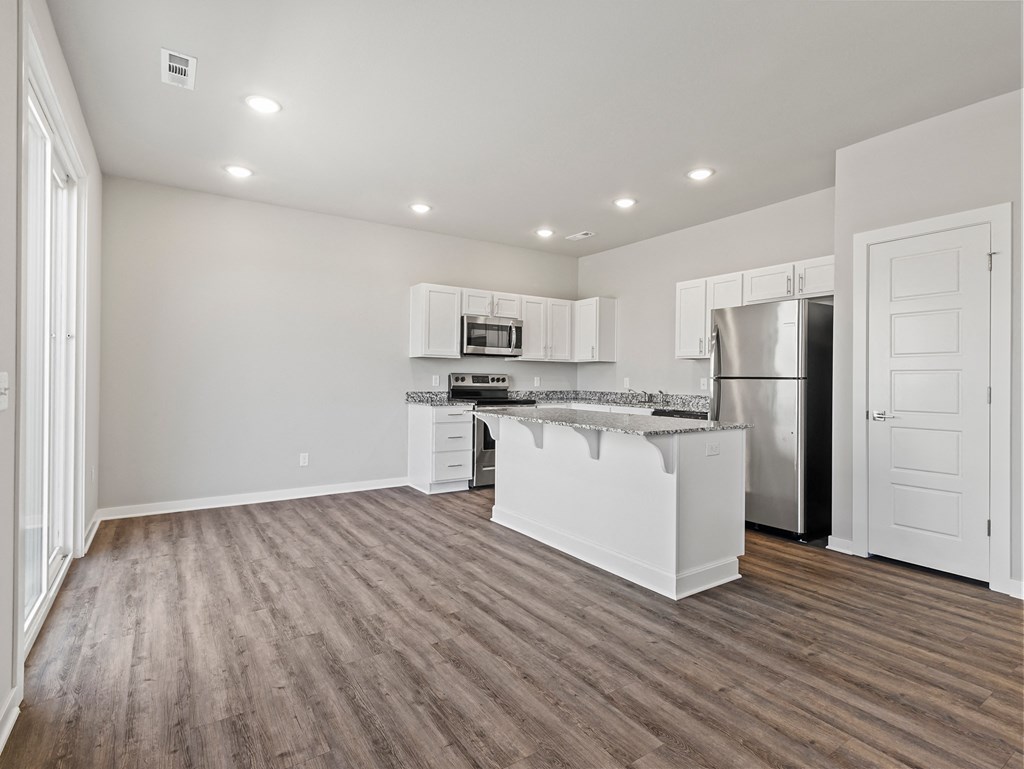 an empty kitchen with white cabinets and a stainless steel refrigerator at Hillcrest Village, Springdale, AR 72762