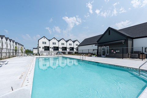 A swimming pool in front of a building with a clear blue sky.