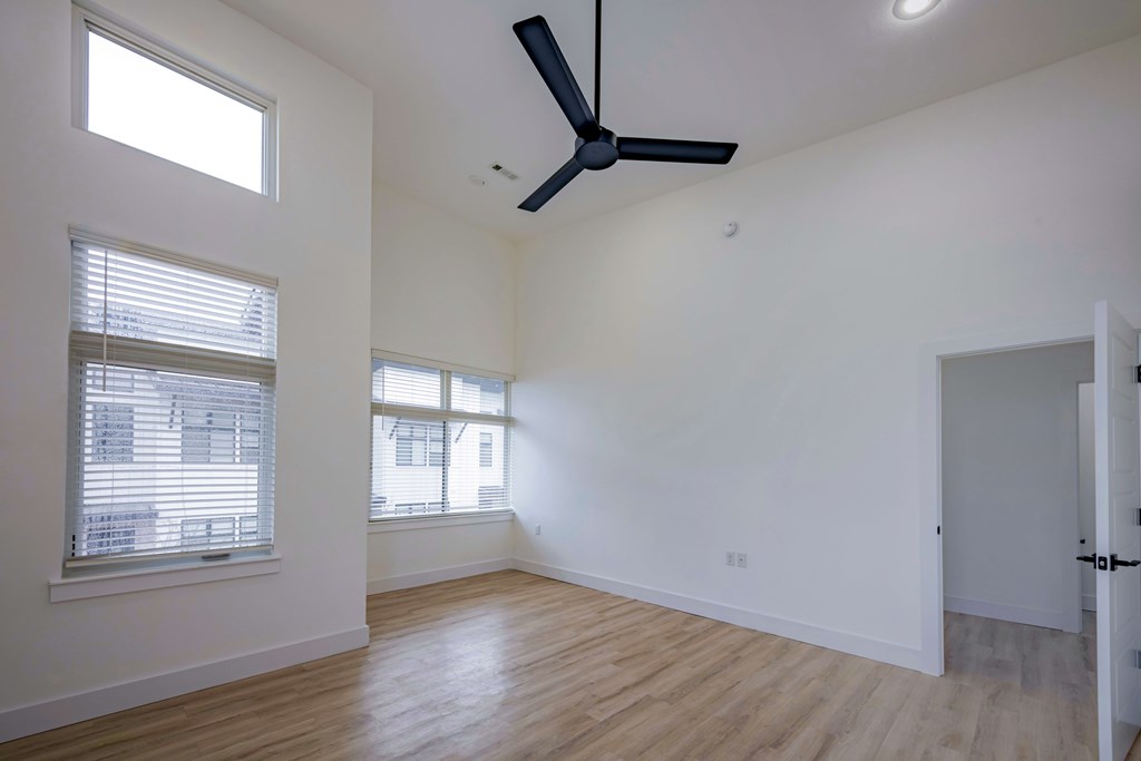 A room with a ceiling fan and two windows.