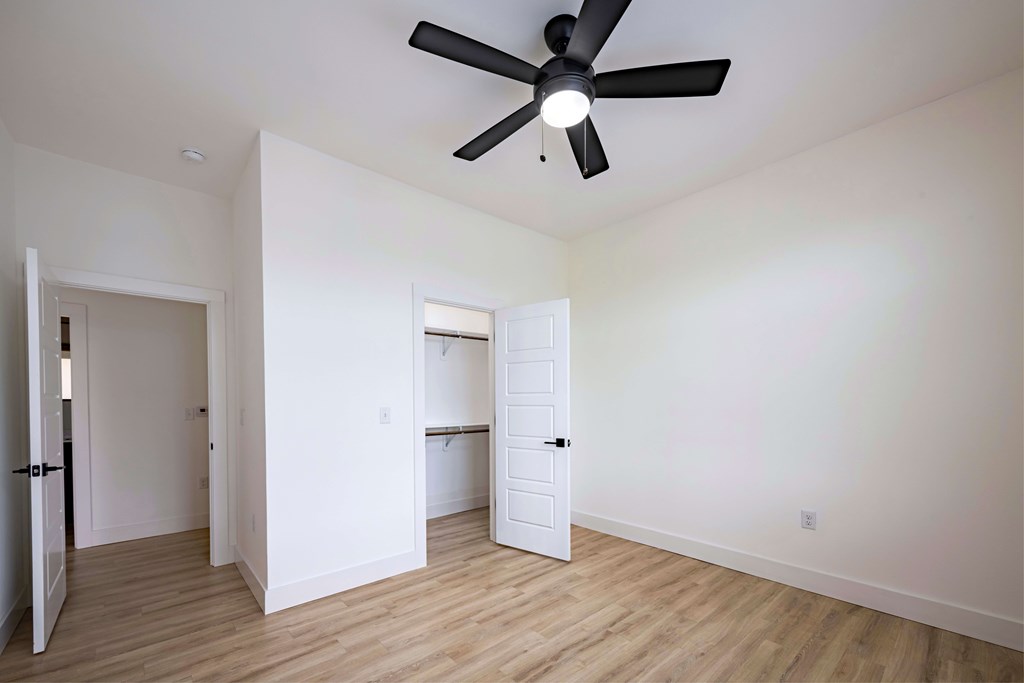 A room with a ceiling fan and wooden floors.