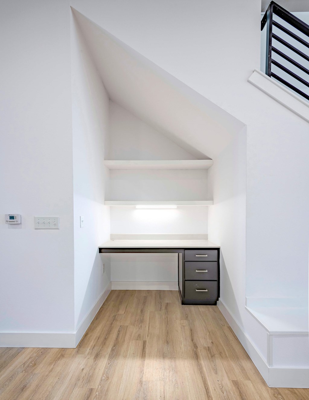 A white room with a desk and drawers.