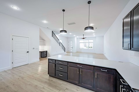 A kitchen with a white counter top and dark brown cabinets.