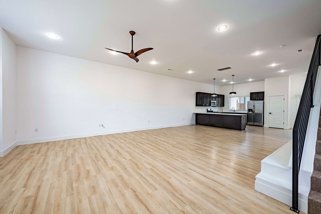 A room with a ceiling fan and wooden flooring.
