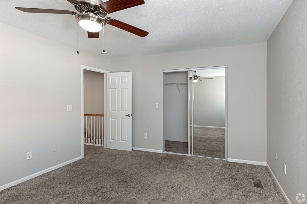 A room with a ceiling fan and two doors, one of which is open.