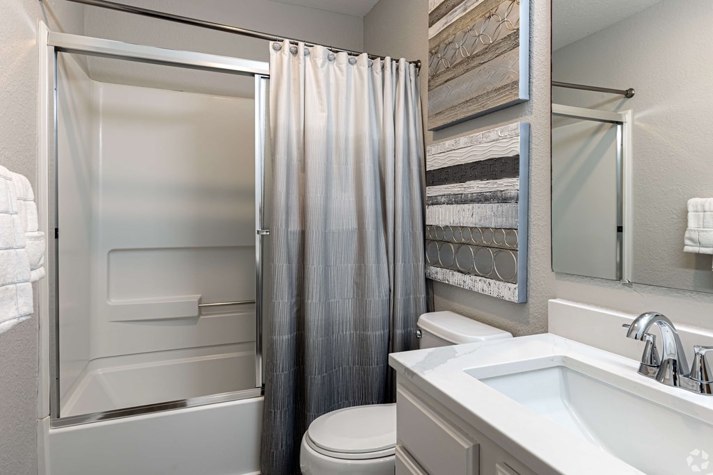 A bathroom with a toilet, sink, and shower.