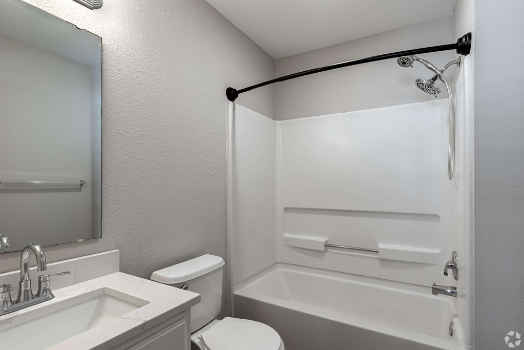A white bathroom with a toilet, sink, and bathtub.