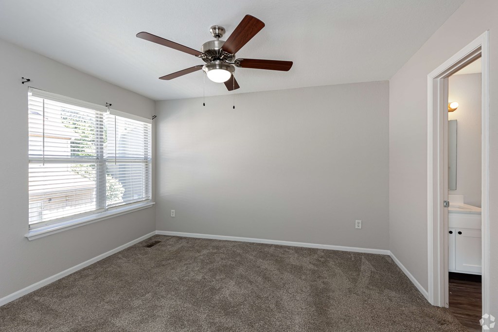 A room with a ceiling fan and carpeted floor.