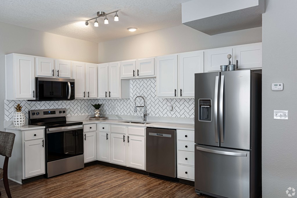 A kitchen with white cabinets and a black fridge.
