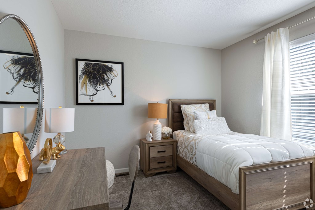 A bedroom with a large bed, a wooden nightstand, and a mirror on the wall.