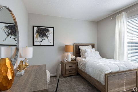 A bedroom with a large bed, a wooden nightstand, and a mirror on the wall.