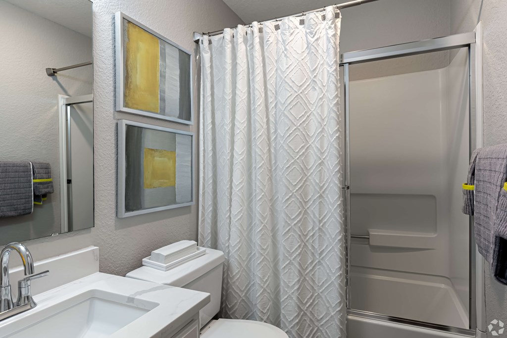 A white bathroom with a sink, toilet, and shower.