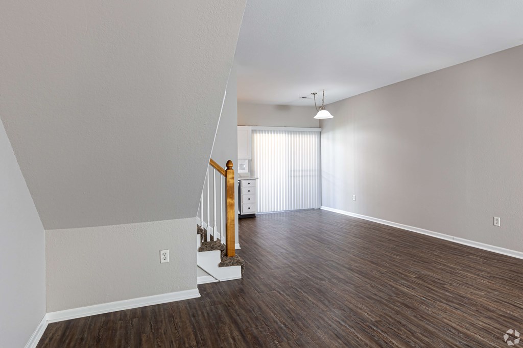 A room with wooden floors and a staircase with a wooden railing.