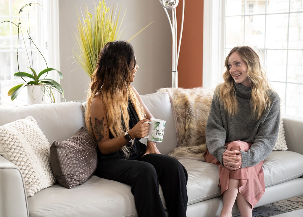 two women sitting on a couch talking