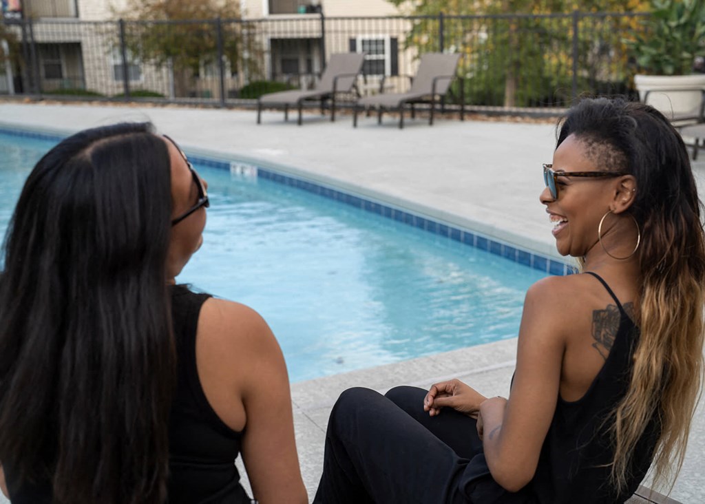 two women sitting next to a pool