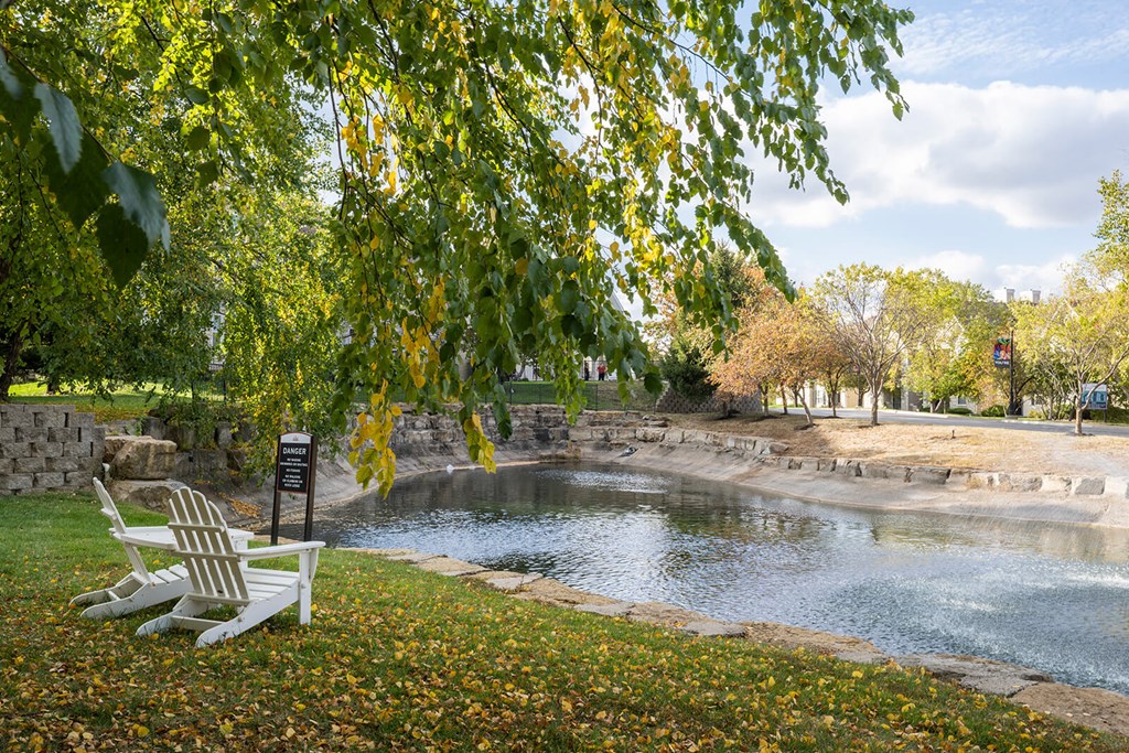 a bench sits next to a pond in a park
