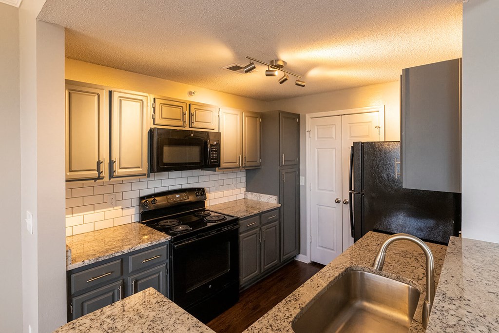 a kitchen with gray cabinets and black appliances