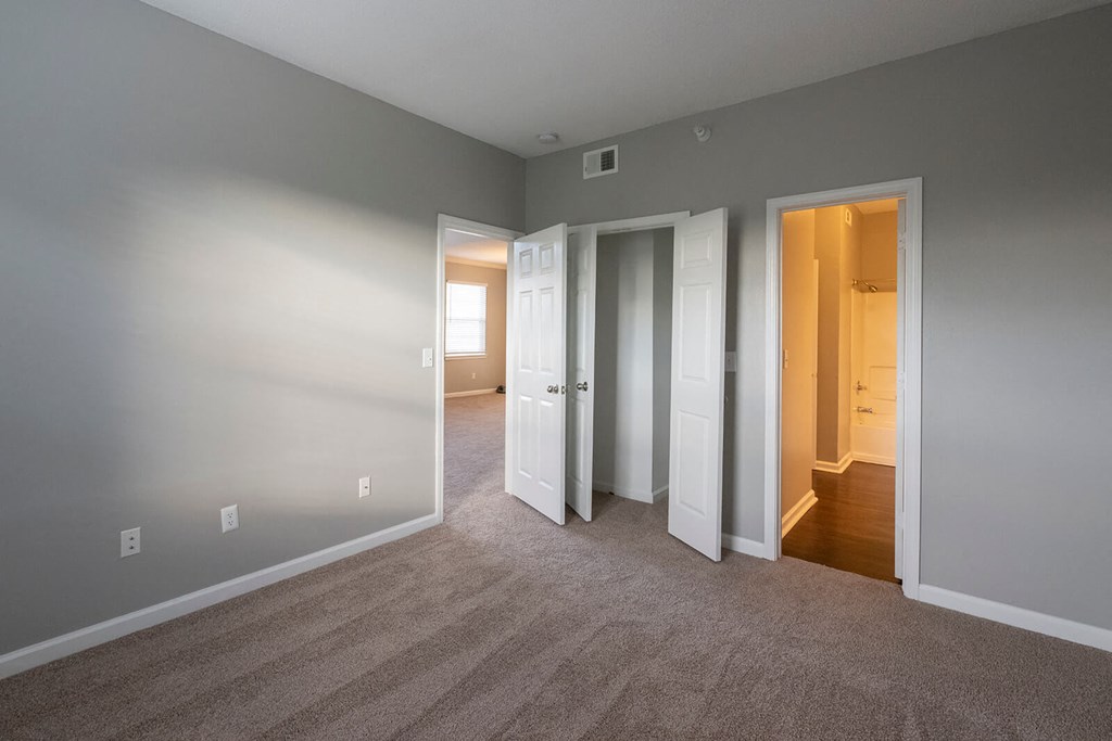 a bedroom with three doors and a carpeted floor