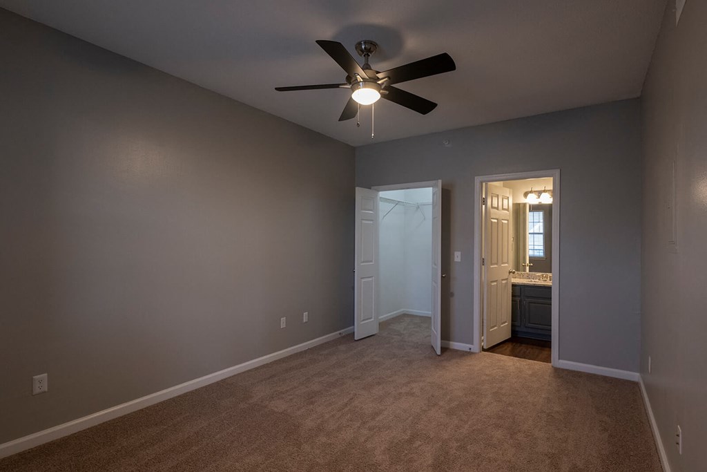 a bedroom with a ceiling fan and a doorway to a bathroom