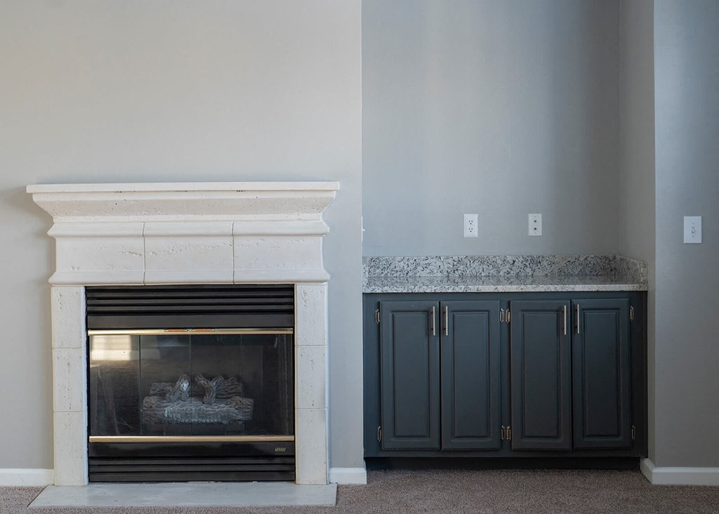 a fireplace with a mantel and a pair of cabinets next to it