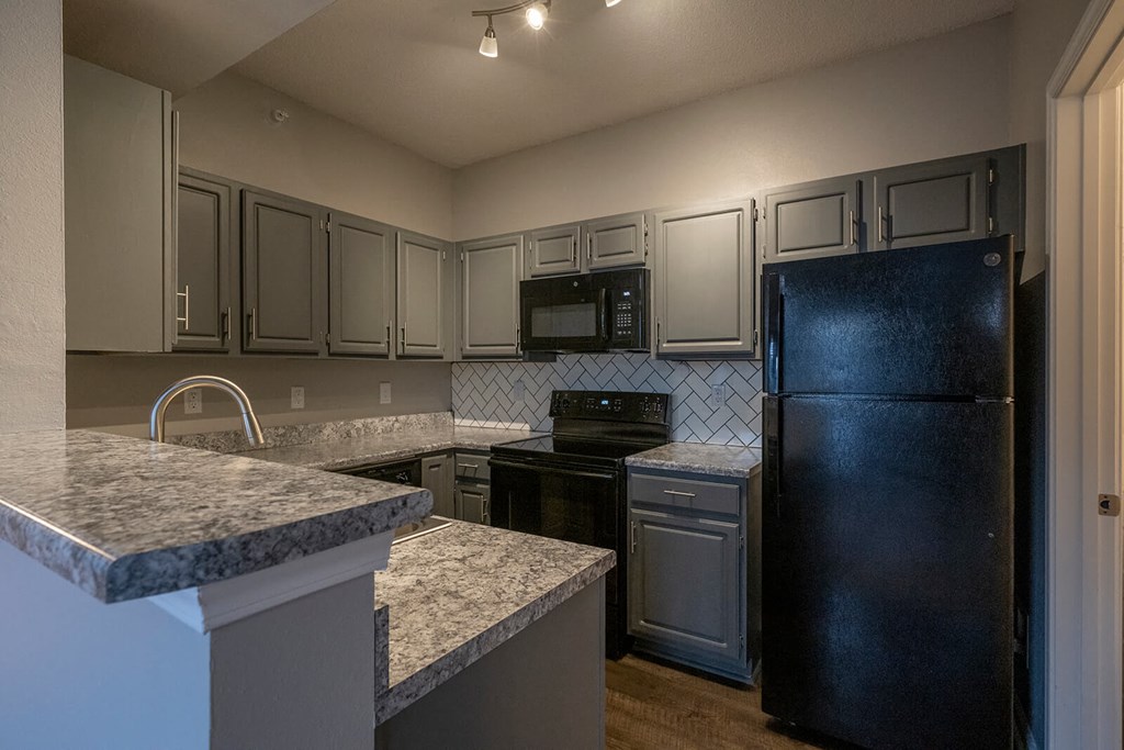 a kitchen with gray cabinets and black appliances