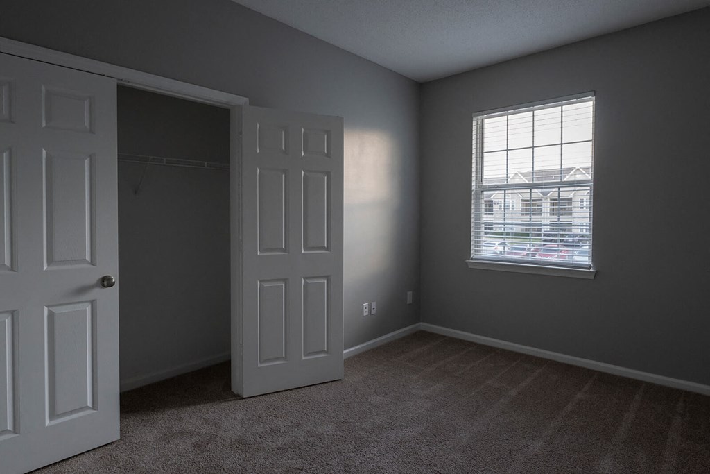 an empty bedroom with a white door and a window