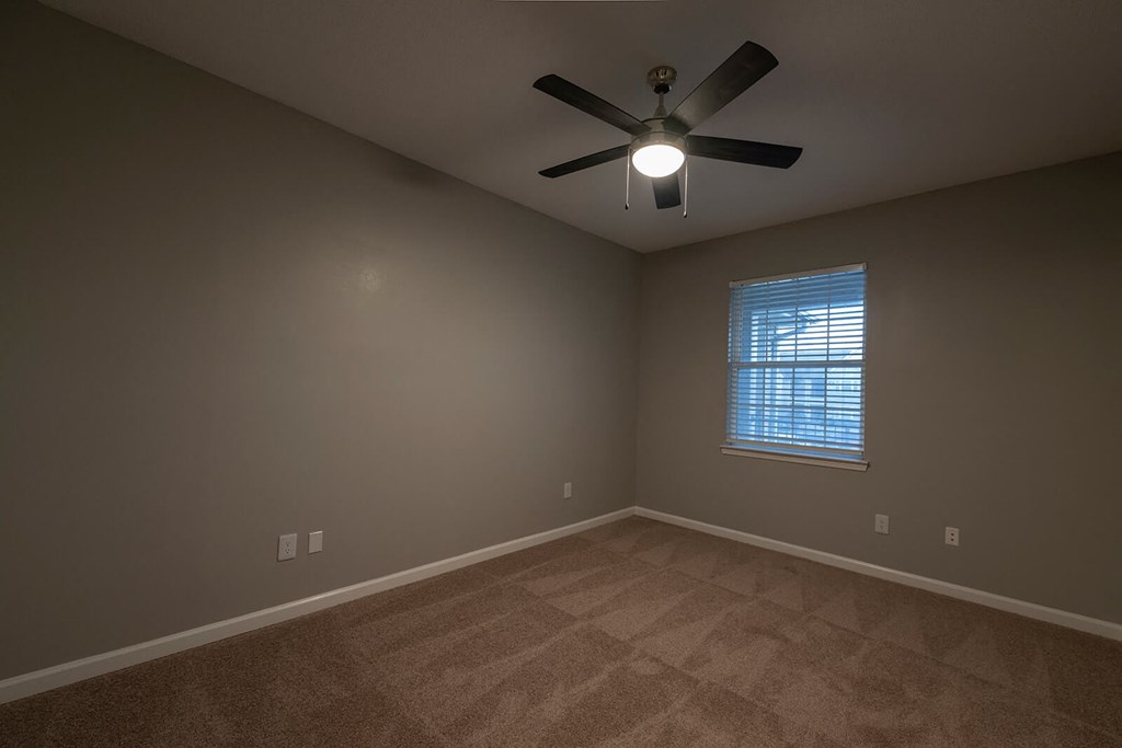an empty room with a ceiling fan and a window