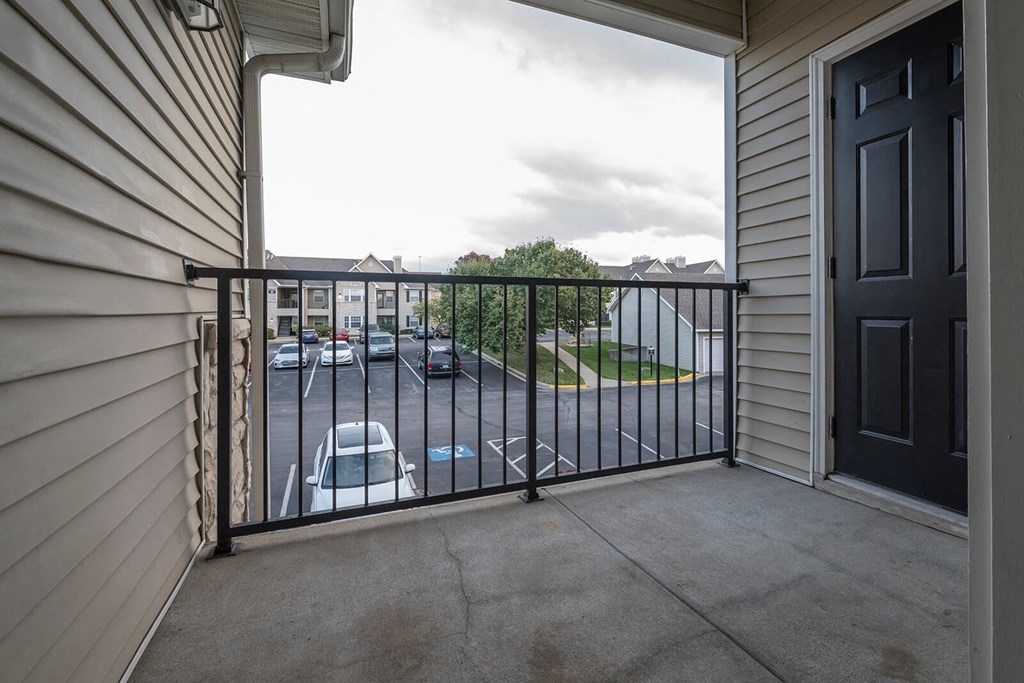a balcony with a black railing and a parking lot in the background
