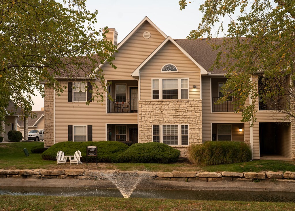 Pond with water fountain and apartments in background