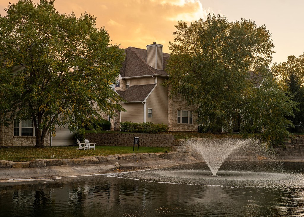 a fountain in a pond with a house in the background