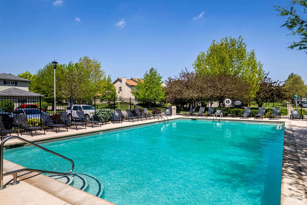 A large swimming pool surrounded by chairs and trees.