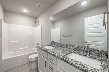 a bathroom with two sinks and a toilet and a bath tub