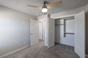 an empty bedroom with a ceiling fan and a closet