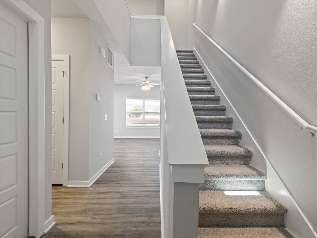 a view of a staircase in a townhome with carpeted stairs and a ceiling fan at Hillcrest Village, Springdale, AR