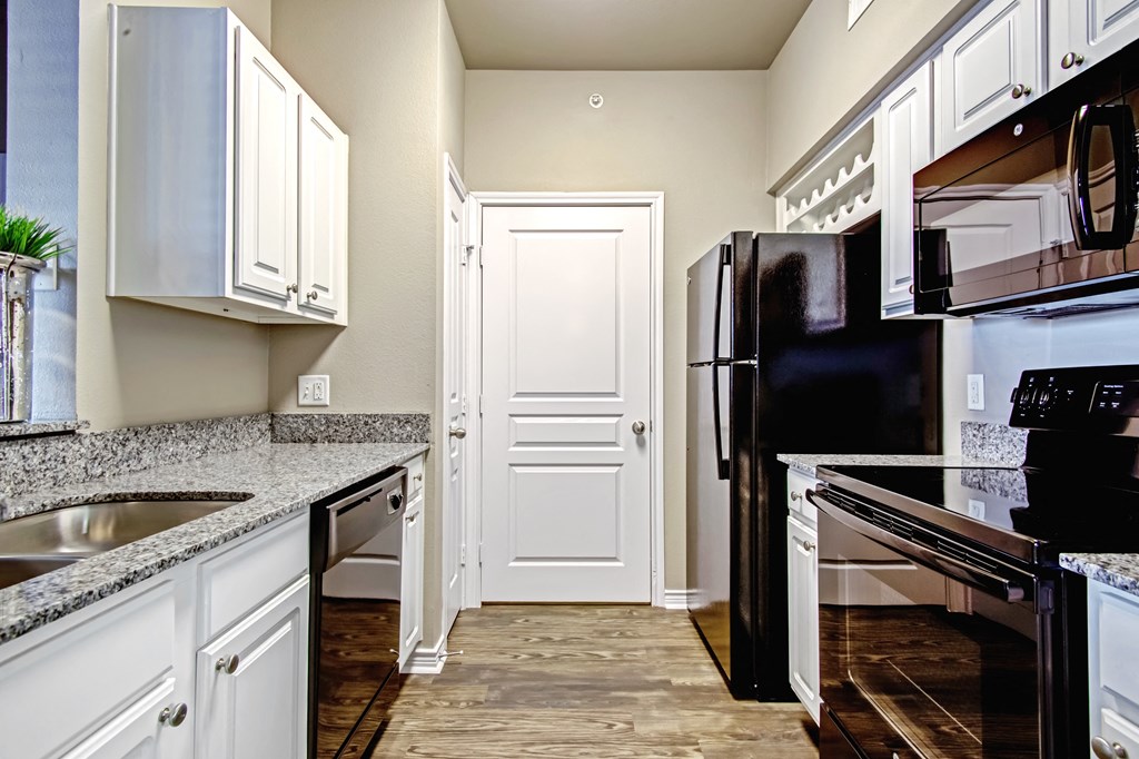 kitchen in one bedroom floorplan with black appliances and wood flooring and granite countertops