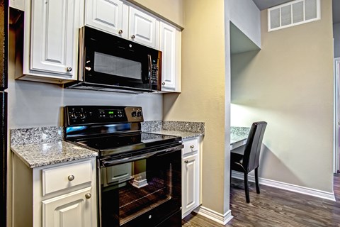 a kitchen with a stove and microwave and a table with a chair