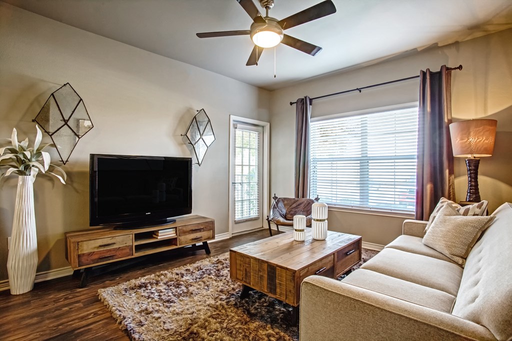 model one bedroom living room with bright window and wood flooring