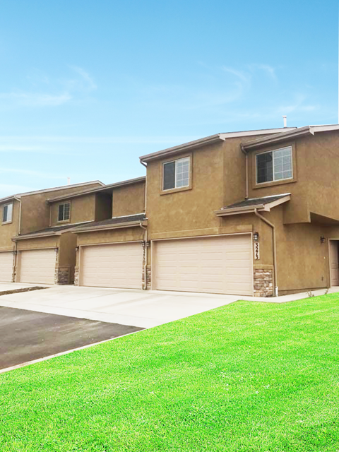 a house with three garage doors and a green lawn