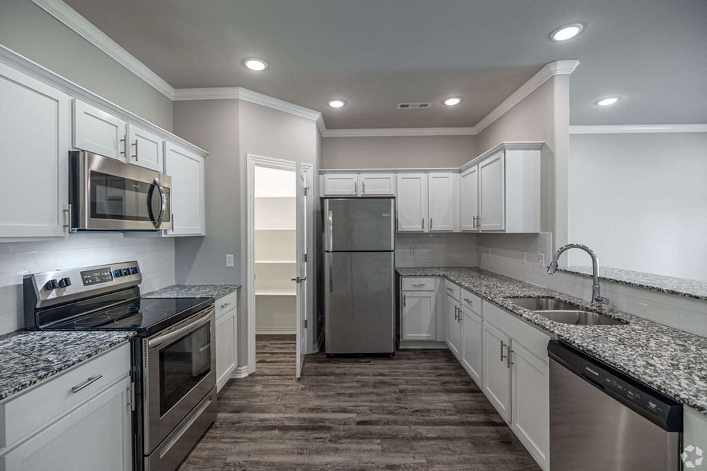 A kitchen with white cabinets and a black countertop.